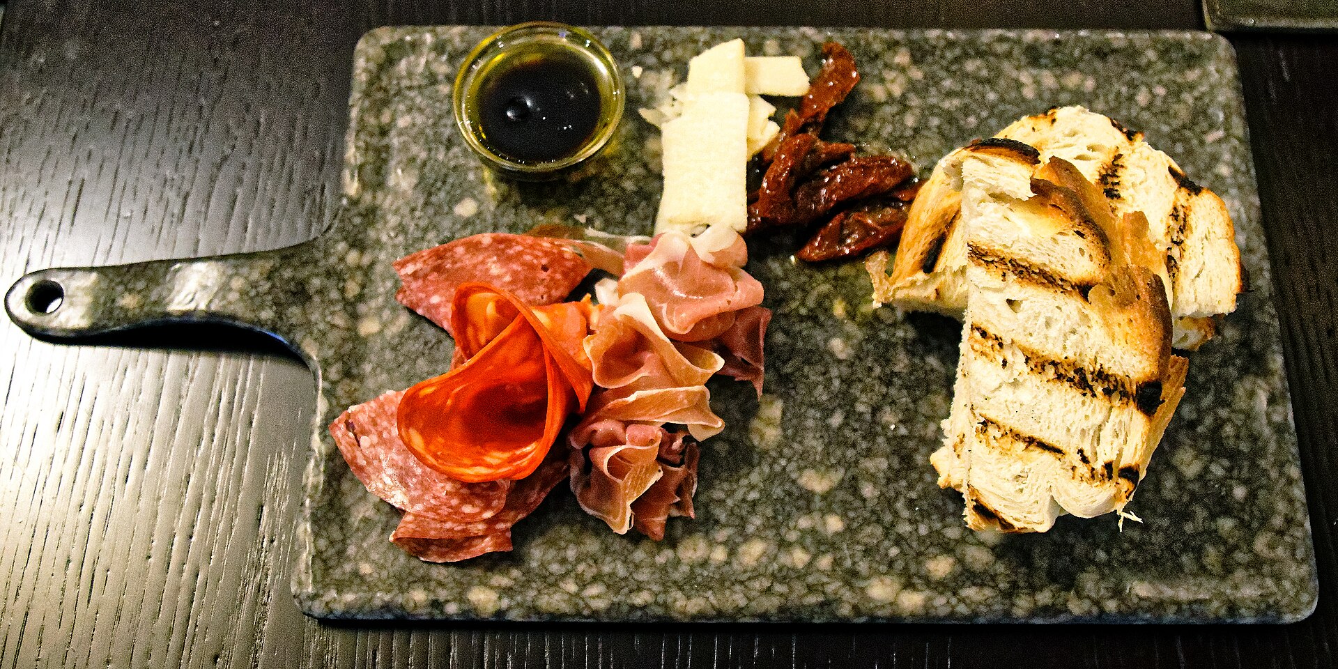 Charcuterie platter with salami rosettes, prosciutto, cheese, and grilled bread